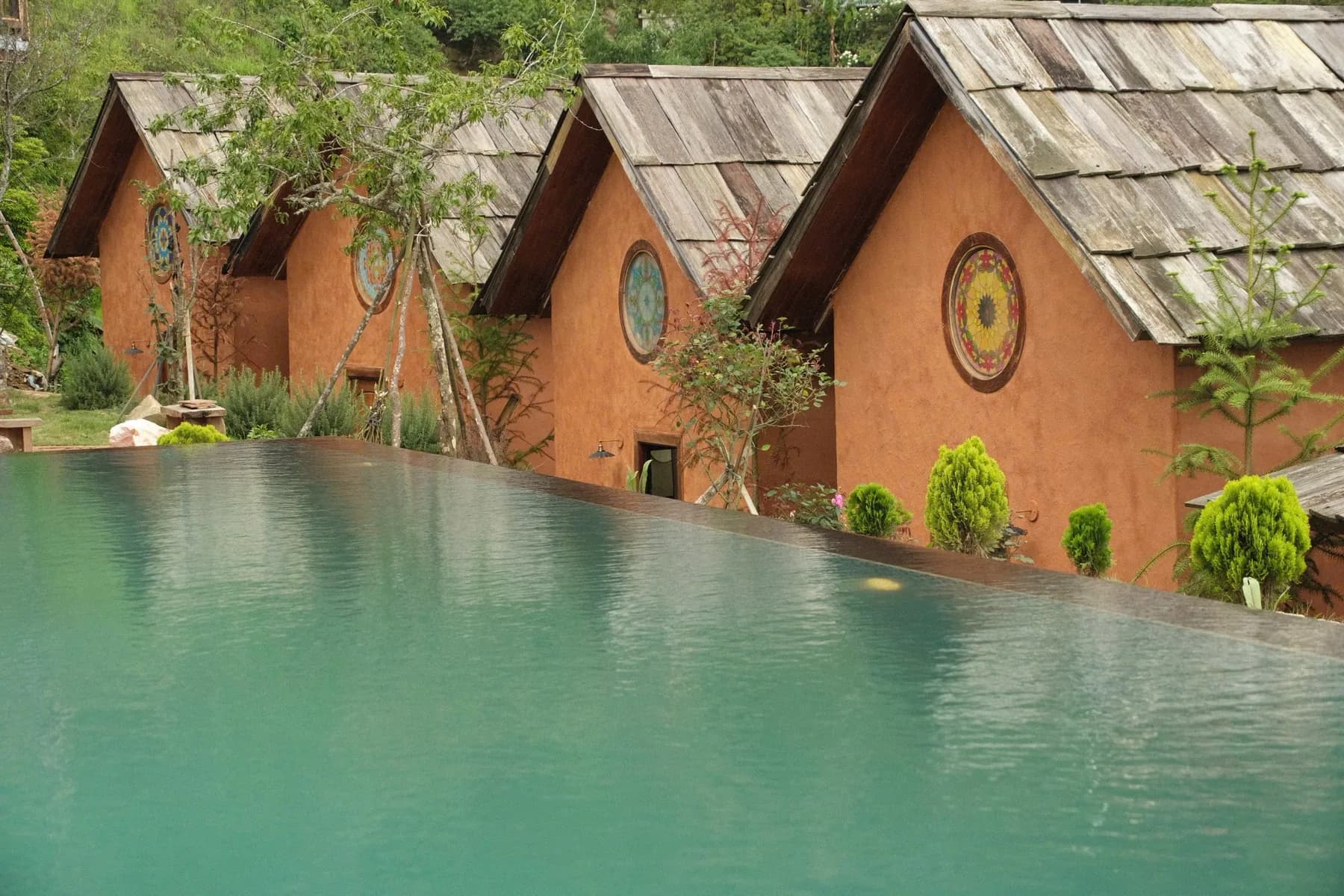 Hồ bơi tràn bờ cạnh dãy bungalow mái gỗ
