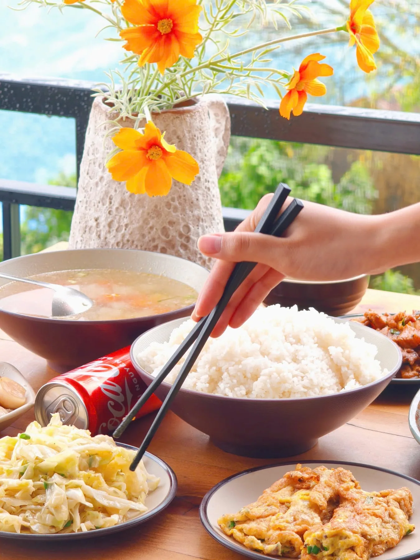 Cơm, canh và các món ăn trên bàn ngoài hiên